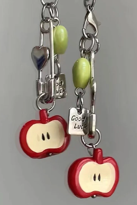 Love and Deepspace Caleb-inspired phone charm, close-up showing red apple design with heart pendant, zinc alloy construction, detailed letterpress printing, collectible fan accessory.