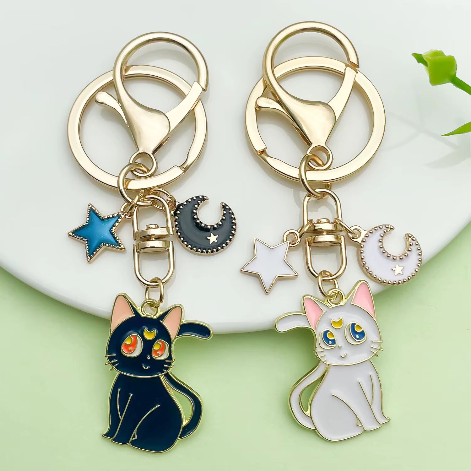 Sailor Moon–inspired enamel keychains featuring Luna or Artemis designs, made from zinc alloy with a smooth enamel finish, shown with individual and paired product images including size dimensions.