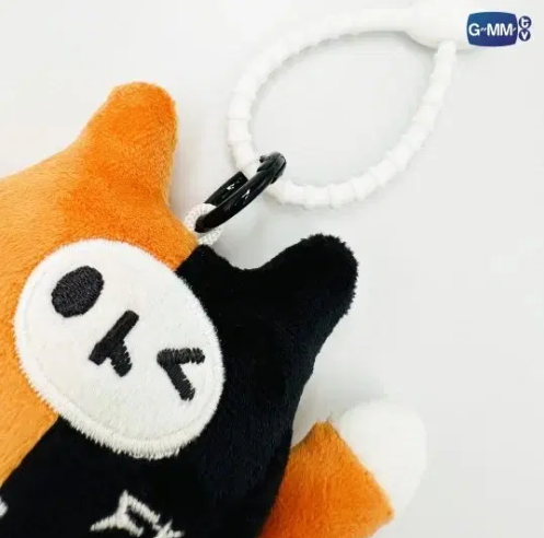 Close-up of the front of the Yuzu Mumu GMMTV plush keychain, showing the orange‑and‑black cat details, texture, and stitching.